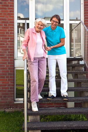 caregiver helping elderly woman down steps