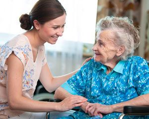 caregiver talking and smiling at elderly woman