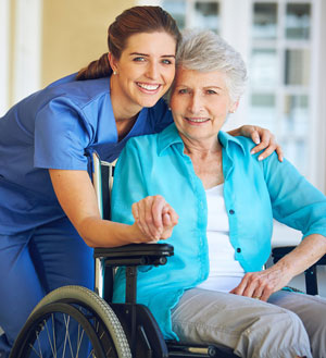 caregiver and elderly woman in wheelchair holding hands